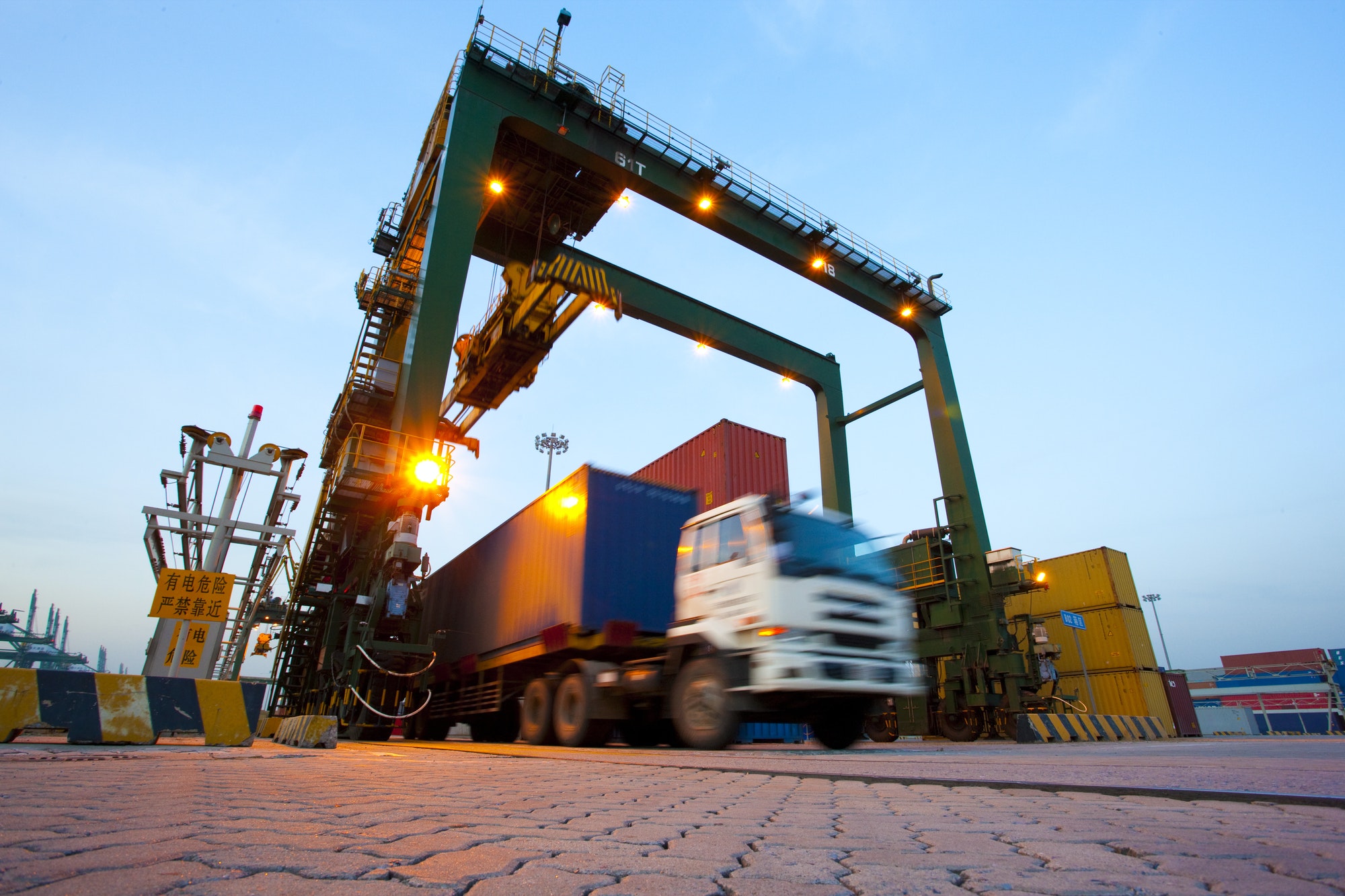 Blurred motion of truck with cargo containers and cranes in a shipping port