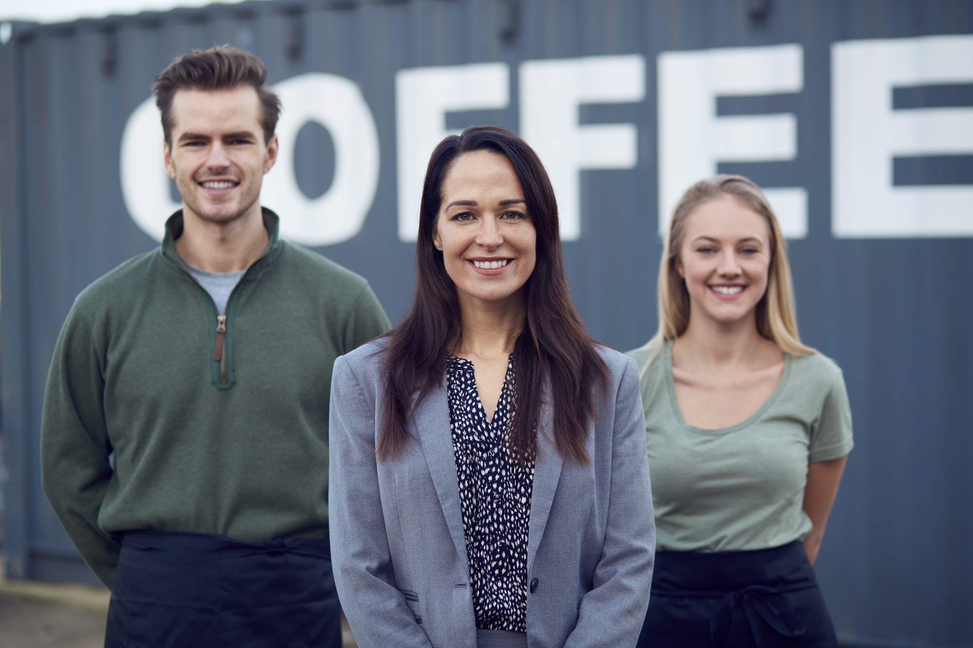 Portrait Of Freight Haulage Team Standing By Shipping Container